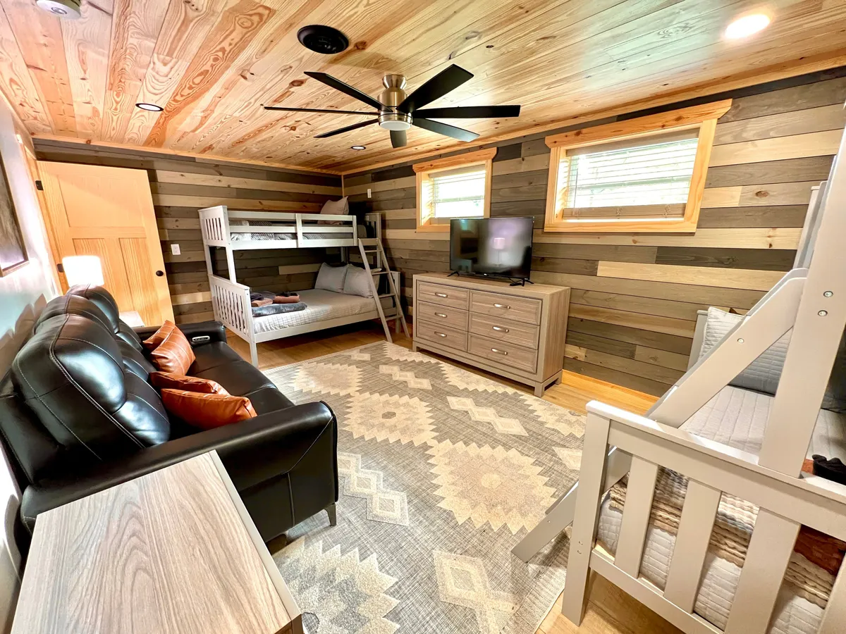 This image shows a bunk bed, television, sofa, and rug arranged to create a lounge-like space perfect for kids or family gatherings. The area is both playful and practical, offering a spot for entertainment and downtime.