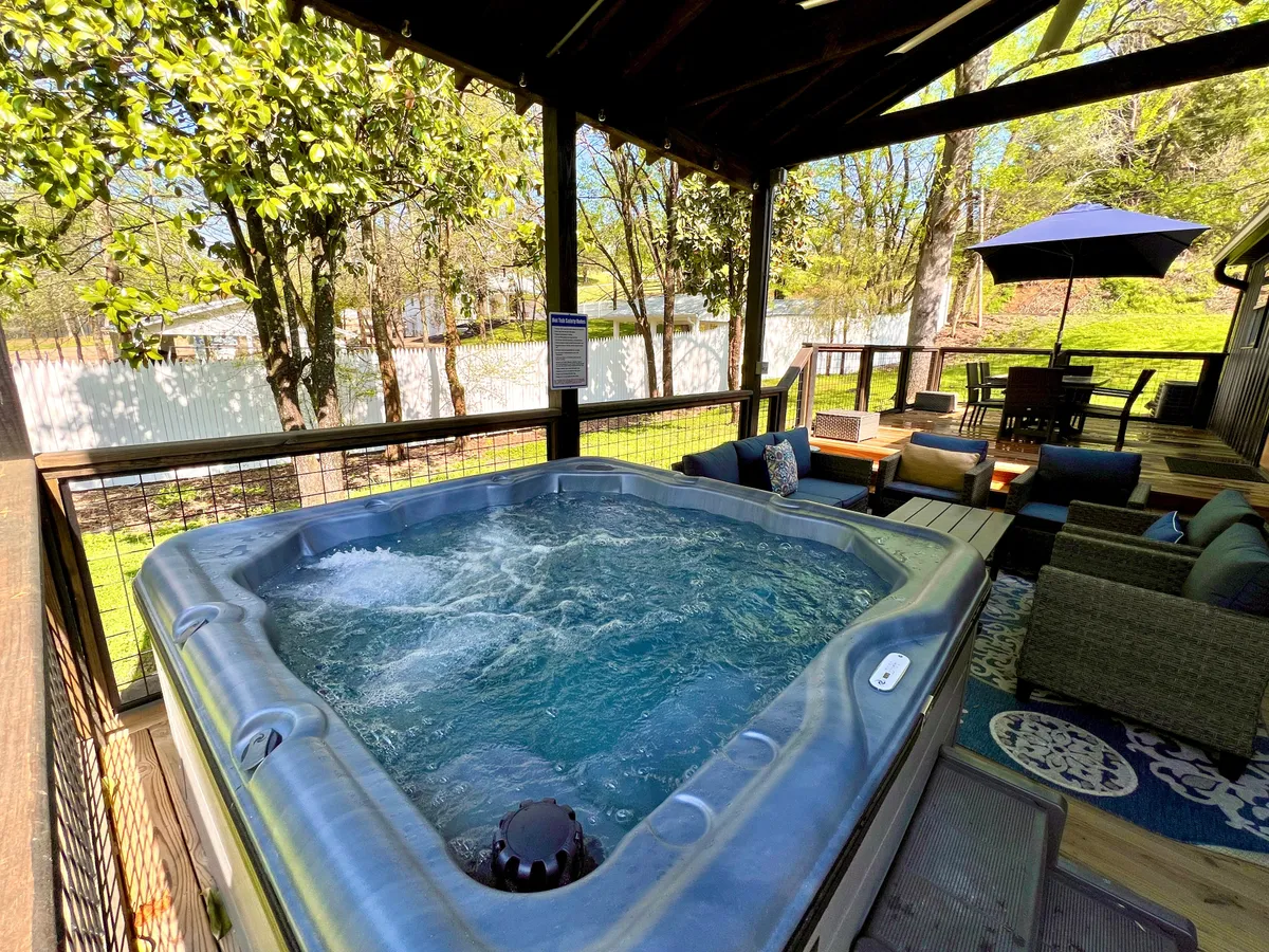 This image captures an inviting outdoor area featuring a hot tub and comfortable seating surrounded by lush greenery. The setting is tranquil, with natural elements and space to relax after outdoor adventures.