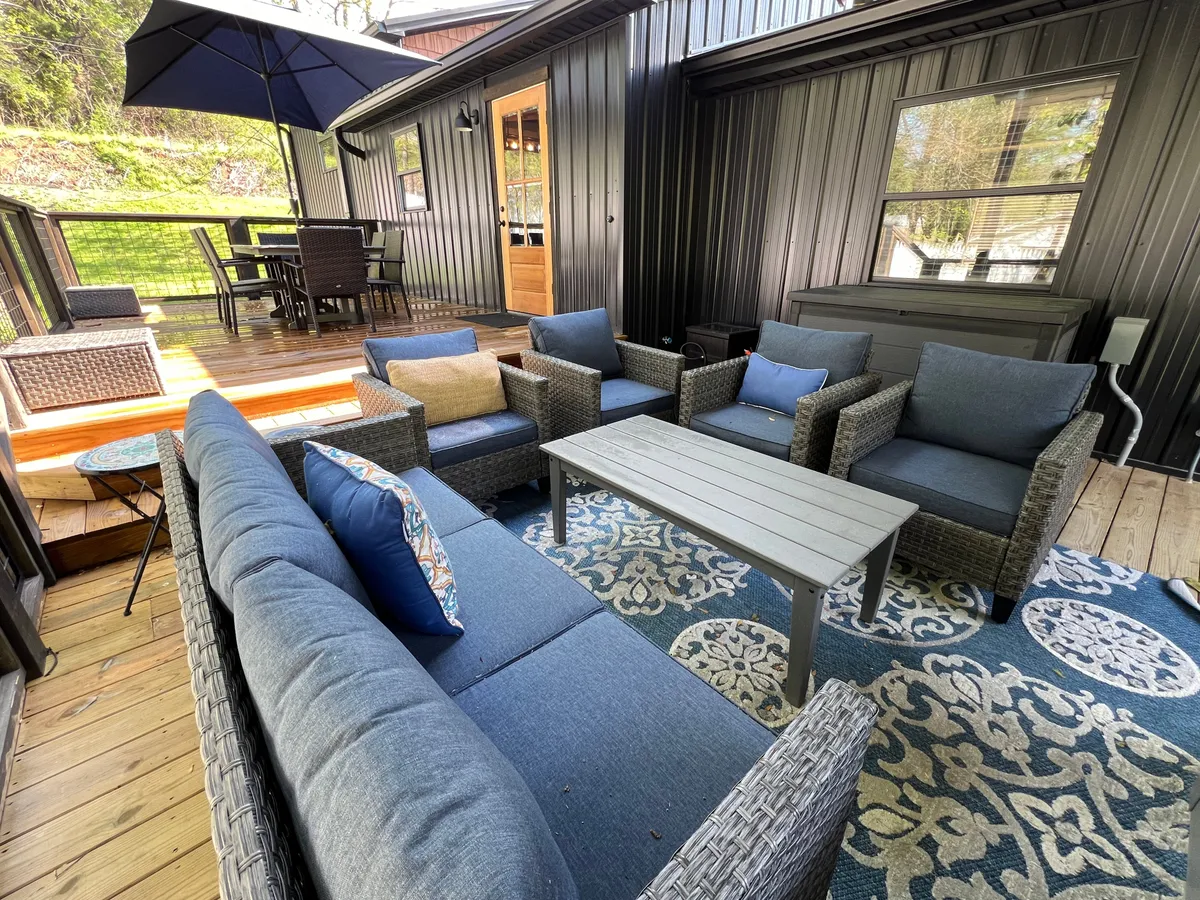 An outdoor setting with comfortable seating, a decorative rug, and large umbrellas providing shade—ideal for group relaxation, outdoor dining, or sharing stories beneath the sky.