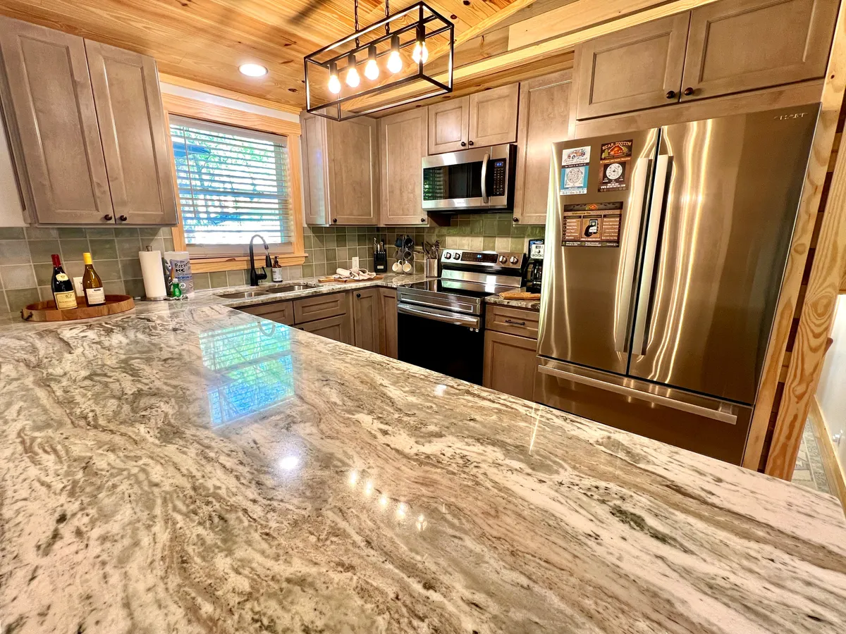 A close-up look at the kitchen, with gleaming granite countertops, stainless steel appliances, and custom wooden cabinetry. The layout is practical and stylish, emphasizing the modern amenities available for cooking and entertaining.