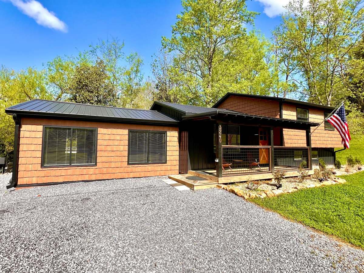 The image showcases the front porch of the property with the American flag, gravel driveway, and unique exterior siding, exuding a welcoming and serene atmosphere. It hints at the property's proximity to family attractions and serves as a symbol of 'coming home' after a day out.